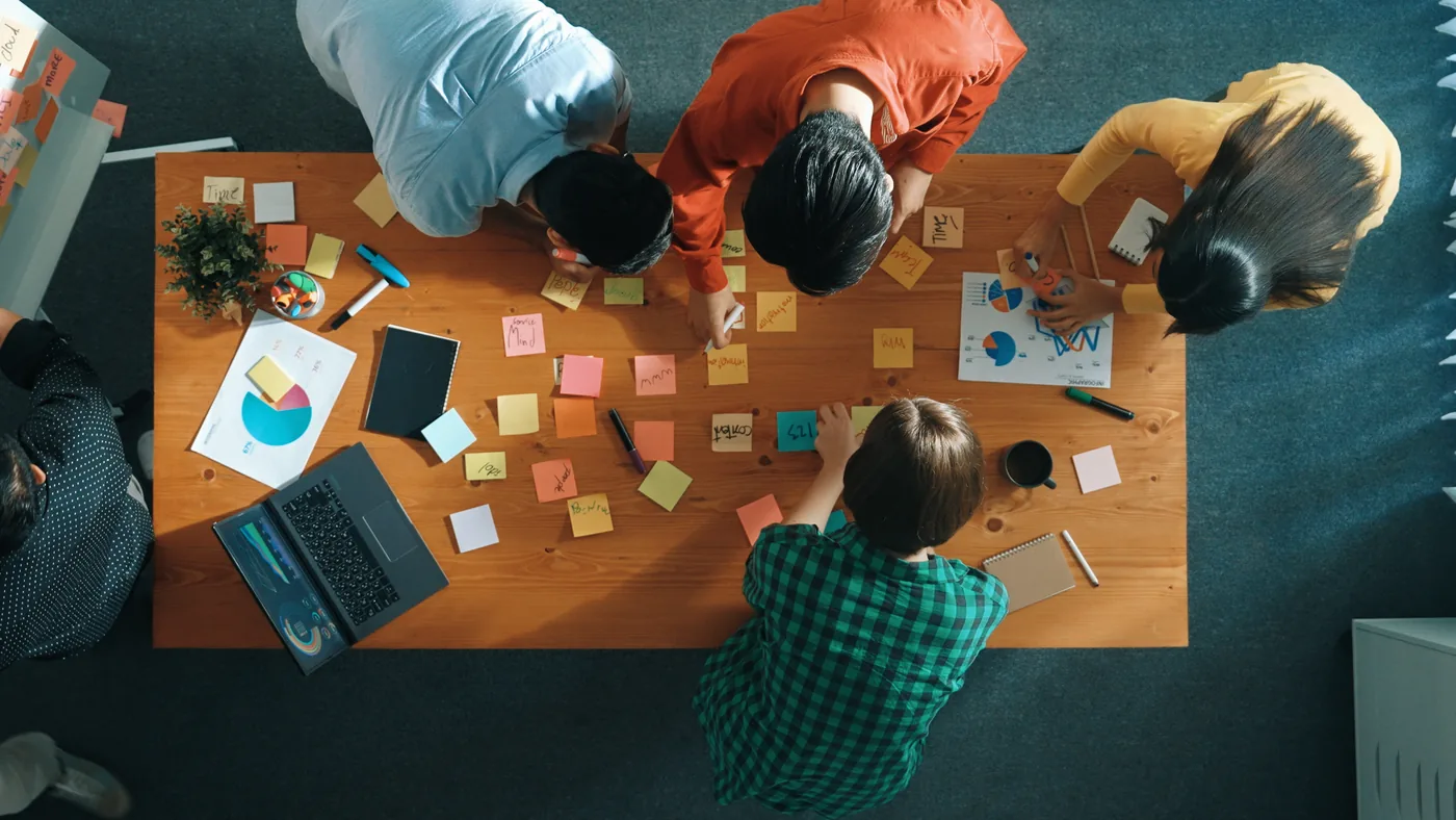 Overhead view of a team collaborating with sticky notes and charts around a table